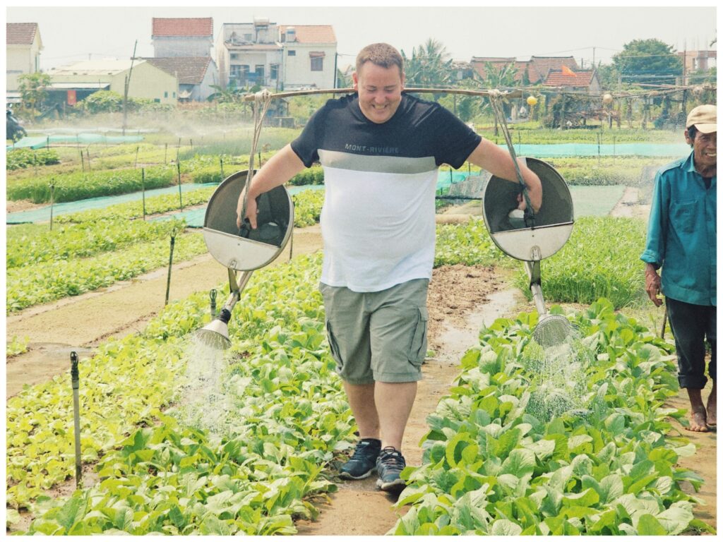 a tourist watering herb gardens at hoi an tra que vegetable village